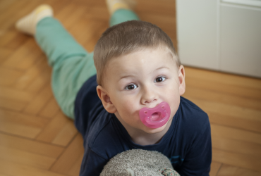 Photo d'un enfant avec sa tétine et son doudou