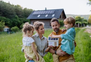 Une famille devant une maison avec des panneaux solaires