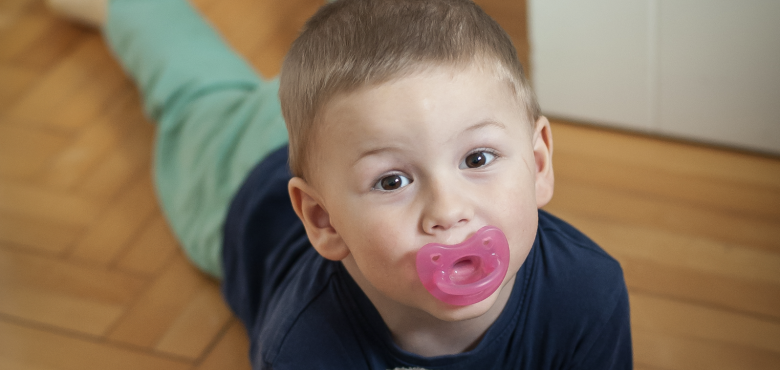 Photo d'un enfant avec sa tétine et son doudou